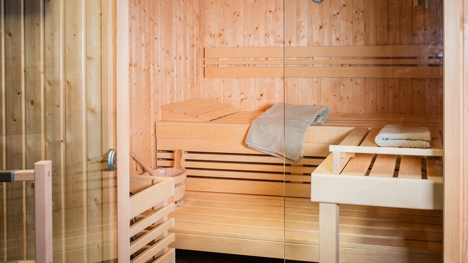 Saunacabine met houten banken naast de badkamer
